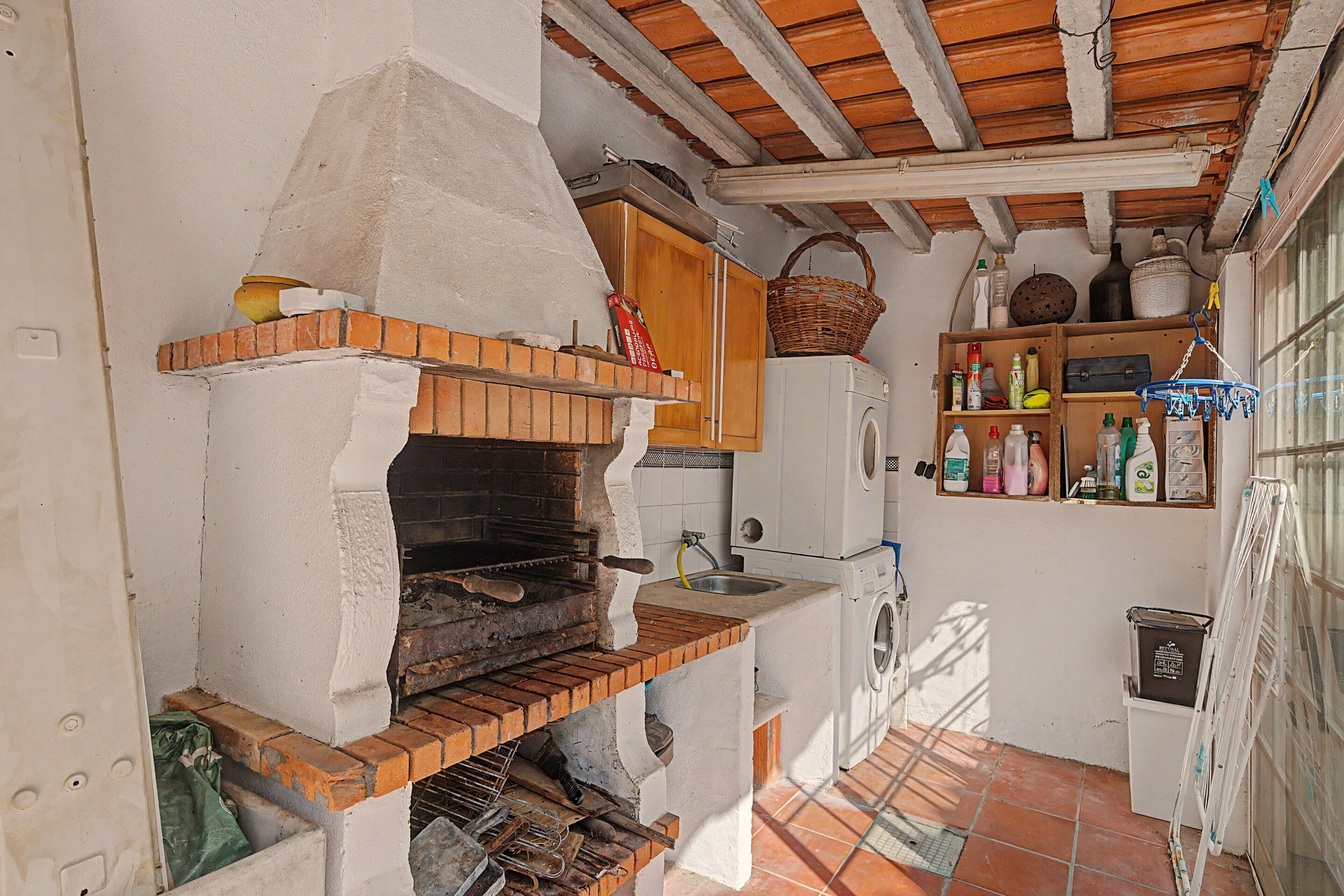 A compact kitchen with a brick oven, wooden cabinets, and a washing machine.