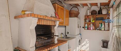 A compact kitchen with a brick oven, wooden cabinets, and a washing machine.