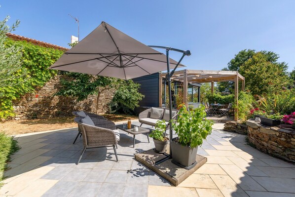 A patio with outdoor furniture, a pergola, and potted plants.