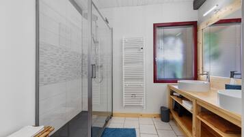 Une salle de bain moderne avec une douche à parois de verre, un meuble-lavabo en bois et une fenêtre équipée de stores.