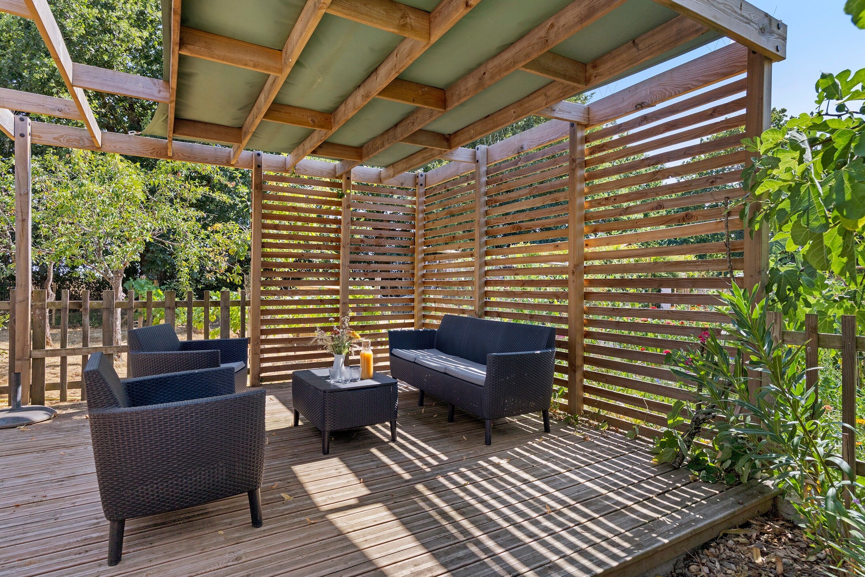 Une terrasse extérieure avec des meubles en bois et une structure en forme de pergola.