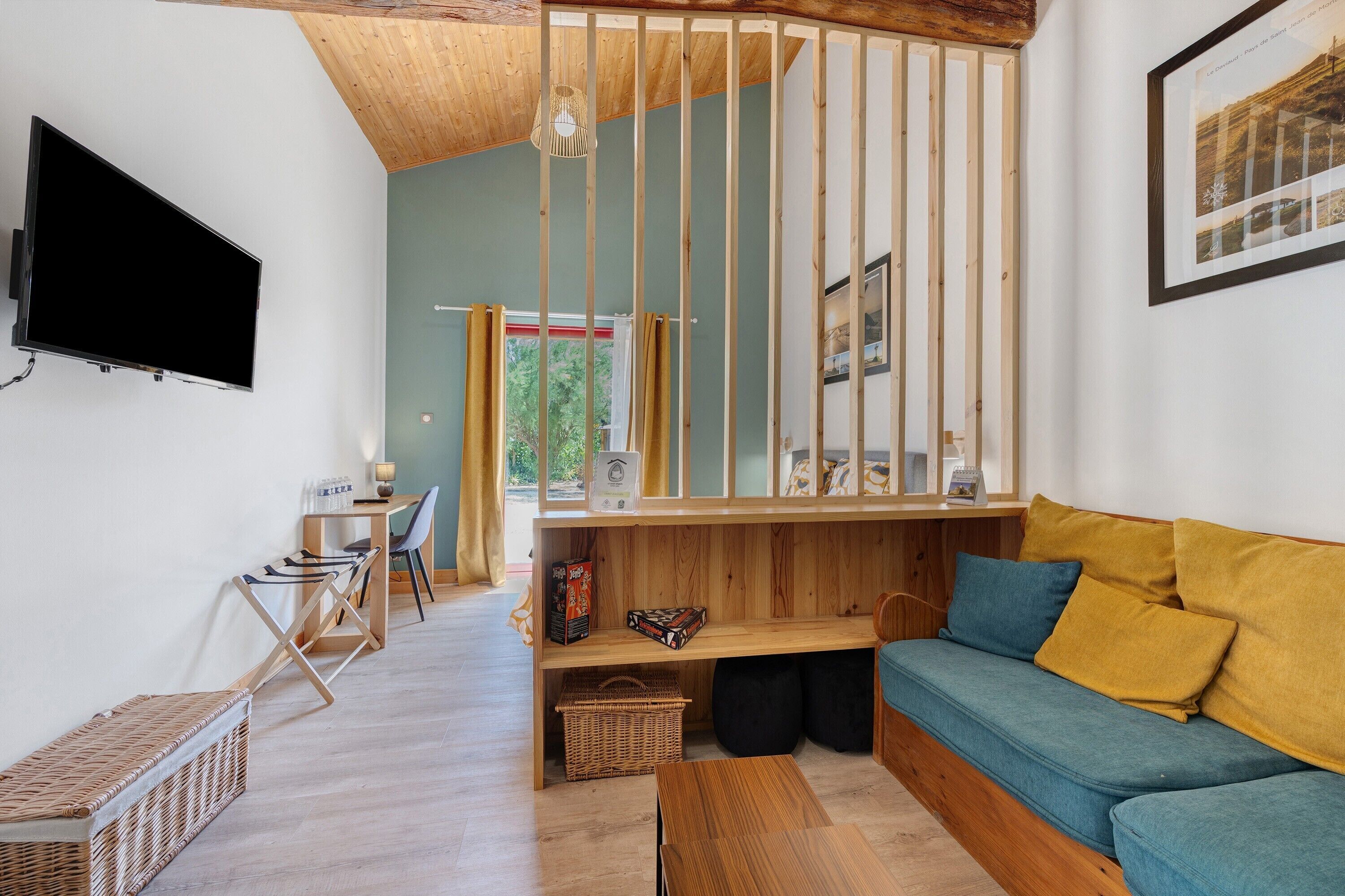 Una sala de estar moderna con techo de madera, un televisor montado en la pared, un sofá con cojines, un comedor con mesa y sillas, y una ventana con cortinas.