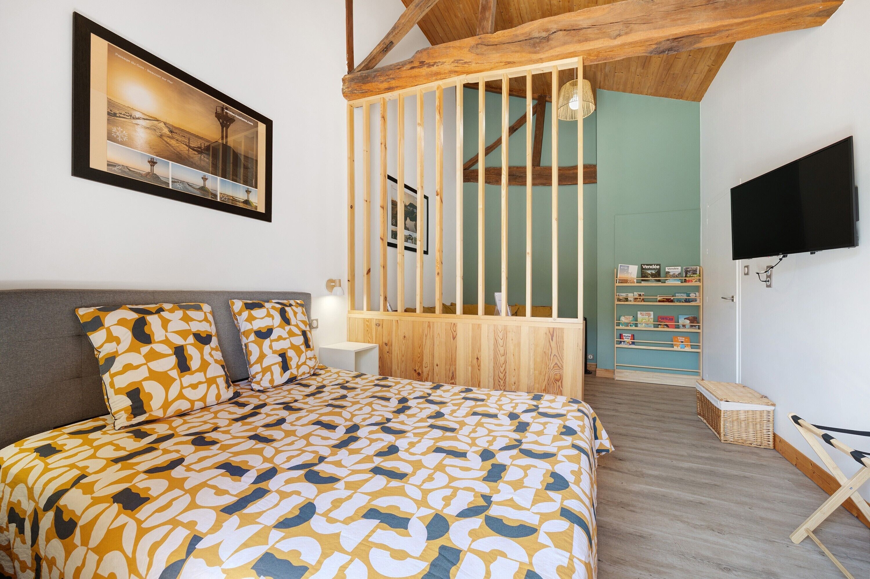 Ein Schlafzimmer mit einem Bett, einem an der Wand befestigten Fernseher, einem Bücherregal und einer Holzwand.
