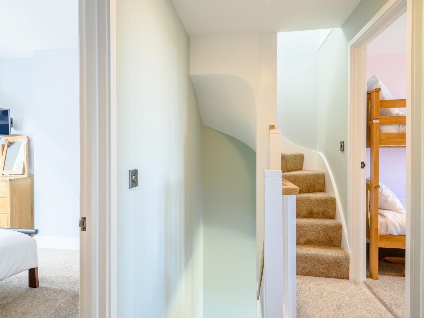 A bedroom with a bunk bed, a desk with a chair, and a door leading to another room.