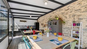 Eine moderne Küche mit Steinwand, Holzschränken und einer Essecke mit Tisch für zwei Personen.