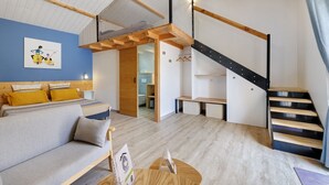 Ein modernes Interieur mit einem Schlafbereich im Loft-Stil, einer Treppe und einem Wohnzimmer mit Sofa und Couchtisch.