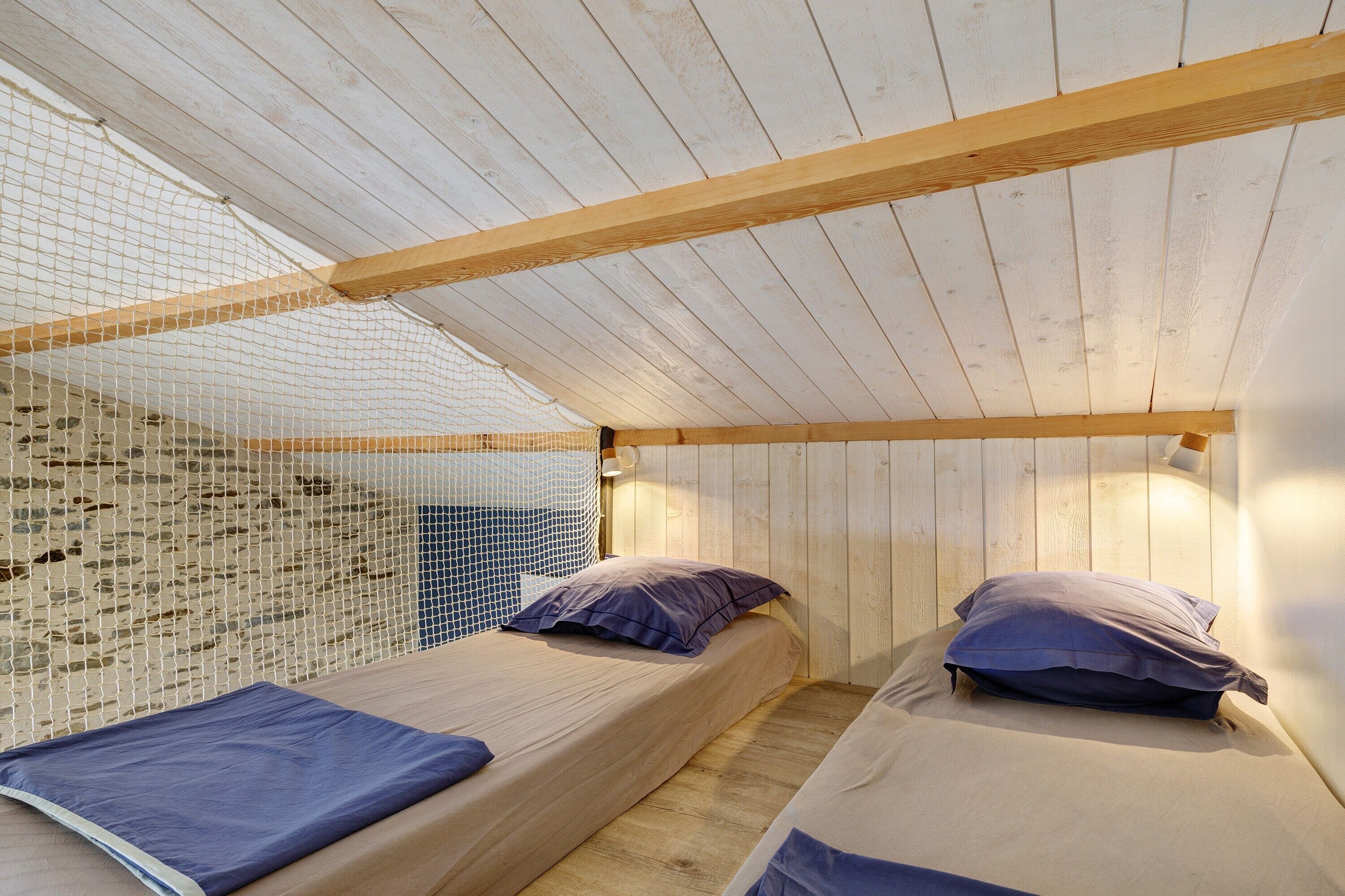 Ein Zimmer mit zwei Betten, Holzbalken und einer Wand mit Moskitonetz.