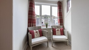 A corner room with two wicker chairs, a window with curtains, and a view of buildings outside. - 5 Bed in Melrose (oc-79418) (Melrose)