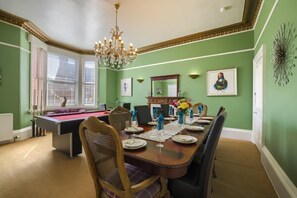 Ein Esszimmer mit Billardtisch, einer Kristallleuchter und einer grünen Wand.