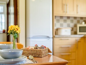 A kitchen with a refrigerator, microwave, and wooden cabinets. - 1 Bed in Conwy (oc-79357) (Ty'n-y-groes)
