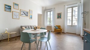 A modern living room with a round dining table, teal chairs, a sofa, and a yellow armchair. - Spacious and Bright, Near Train Station and Palais des Festivals - BENAKEY (Cannes)
