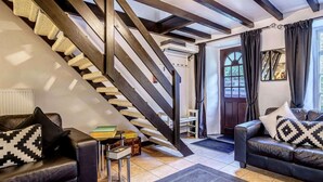 Un salon moderne avec un escalier, des canapés en cuir et une vue sur l’extérieur.