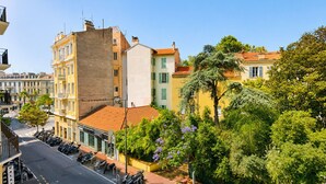 Una vista di strada con auto parcheggiate, una fila di edifici e un marciapiede alberato.