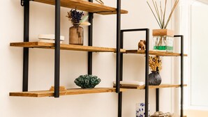 A multi-tiered wooden shelf unit with black metal supports, various decorative items, and a globe. - Sunny Terrace & Open Views | Pool, Parking, A/C | Cannes – BENAKEY (Cannes)