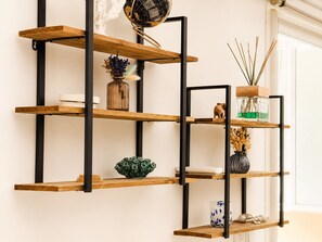 Una estantería de madera en varios niveles con soportes de metal negro, varios objetos decorativos y un globo.