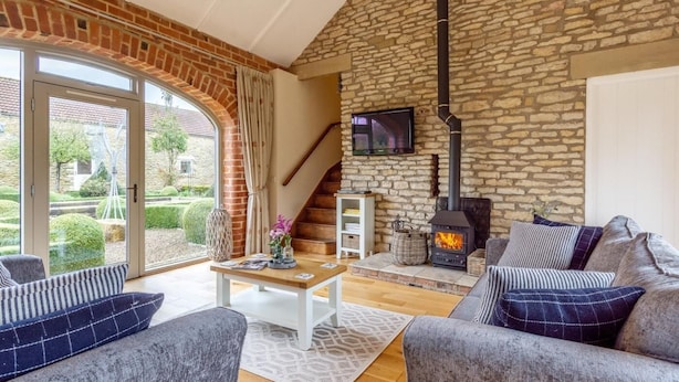 Ein gemütliches Wohnzimmer mit Steinwand, Kamin und Wand-Fernseher.