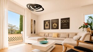 Een moderne woonkamer met een bank, een salontafel en een fauteuil. Er hangen drie ingelijste objecten aan de muur.