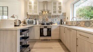 A modern kitchen with a built-in oven, microwave, and a large window. - 2 Bed in Wareham (oc-79228) (West Lulworth)