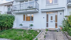 A two-story residential building with a balcony, a front door, and a small garden area. - 2 Bed in Wareham (oc-79228) (West Lulworth)