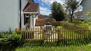 Ein Wohnhaus mit umzäuntem Garten, einer Holzterrasse und einem Garten.