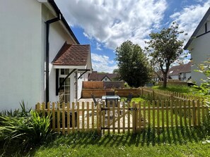 Ein Wohnhaus mit umzäuntem Garten, einer Holzterrasse und einem Garten.