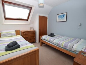 A bedroom with a skylight, a bed with striped bedding, a dresser, a bedside table, and a framed picture on the wall. - 2 Bed in Cardigan (oc-79160) (Blaenannerch)