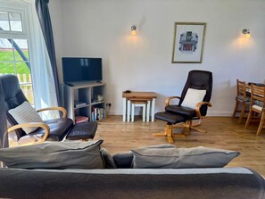 A living room with a sofa, two armchairs, a television, a bookshelf, a small table, and a dining set. - 2 Bed in Cardigan (oc-79160) (Blaenannerch)
