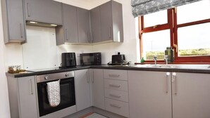 A kitchen with grey cabinets, a microwave, a coffee maker, and a window with a view. - 1 Bed in Launceston (oc-79379) (Davidstow)