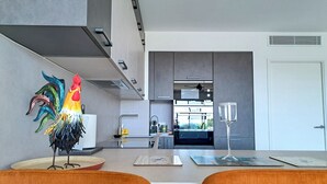 A modern kitchen with a central island, a dining area with two chairs, and a view into the adjacent dining room. - 2B Near Vaugrenier, AC, terrace, sea view, swimming pool, parking- BENAKEY (Villeneuve-Loubet)