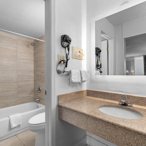 Un baño con bañera, inodoro, lavamanos y espejo.