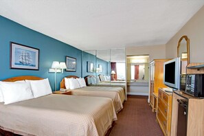 Une chambre d’hôtel avec deux lits, une télévision, un miroir et une commode.