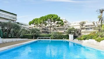 A swimming pool with a tree in the center, surrounded by a building with multiple balconies.