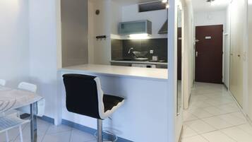 A modern kitchen with a bar stool, a dining table, and a microwave.