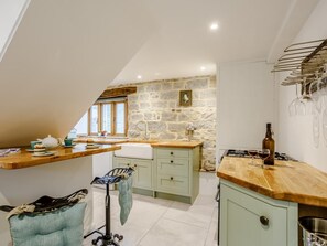 A kitchen with a stone wall, wooden countertops, and a window with a view. - 1 Bed in Glastonbury (oc-79123) (Glastonbury)