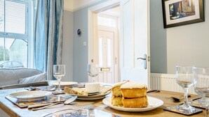 A dining table set with plates, glasses, and cutlery, with a cake and a window in the background. - 3 Bed in Narberth (oc-79443) (Narberth)