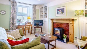 A cozy living room with a fireplace, a television, and a dining area with a table and chairs. - 3 Bed in Narberth (oc-79443) (Narberth)