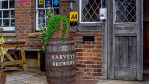 En byggnad av tegel med en trätunna som är märkt med texten ”HARVEYS BREWERY” och en skylt som visar ”AA” och ”STAY”.