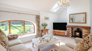 A spacious living room with a large window, a fireplace, a television, and a comfortable seating area. - 2 Bed in Driffield (oc-79279) (Wold Newton)
