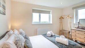 Un dormitorio con cama, cómoda, ventana y radiador.