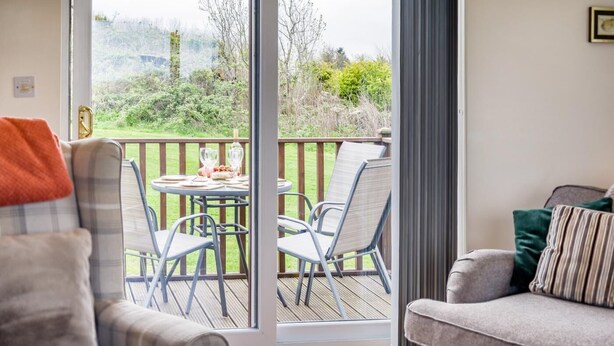 Una habitación con puerta corrediza de vidrio que da a un patio exterior con mesa y sillas.
