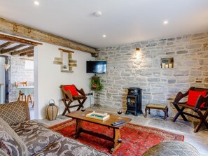A cozy living room with a stone wall, a fireplace, a television, and comfortable seating. - 2 Bed in Glastonbury (oc-79122) (Glastonbury)