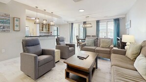 Una sala de estar moderna con un sofá, sillones, una mesa de centro y un comedor con una mesa y sillas.