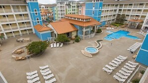 Un patio de hotel con varias piscinas, sillones de descanso y una fuente central.