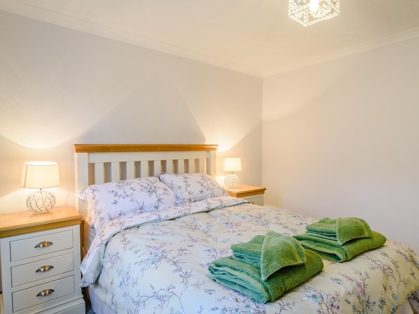Ein Schlafzimmer mit einem Bett, zwei Nachttischen und einer Lampe.