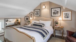 Una camera da letto con un letto grande, comodini, una sedia e quadri appesi alle pareti.