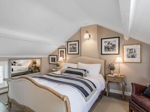 Ein Schlafzimmer mit einem großen Bett, Nachttischen, einem Sessel und gerahmten Bildern an den Wänden.