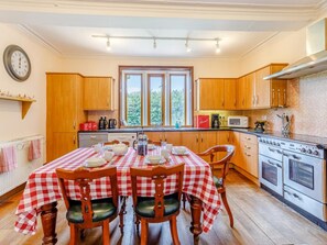 A kitchen with a checkered tablecloth, wooden cabinets, a stove, and a window with a view. - 8 Bed in Rugeley (oc-79321) (Abbots Bromley)