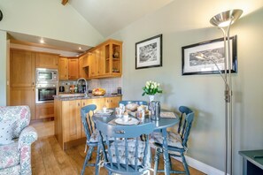 A compact kitchen with wooden cabinets, a built-in oven, and a dining area with a round table and chairs. - 2 Bed in Huby (oc-79166) (Weeton)