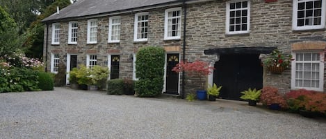 A stone building with multiple windows and a gravel driveway.