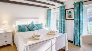 Een slaapkamer met een bed, nachtkastjes, een raam met gordijnen en een foto aan de wand.